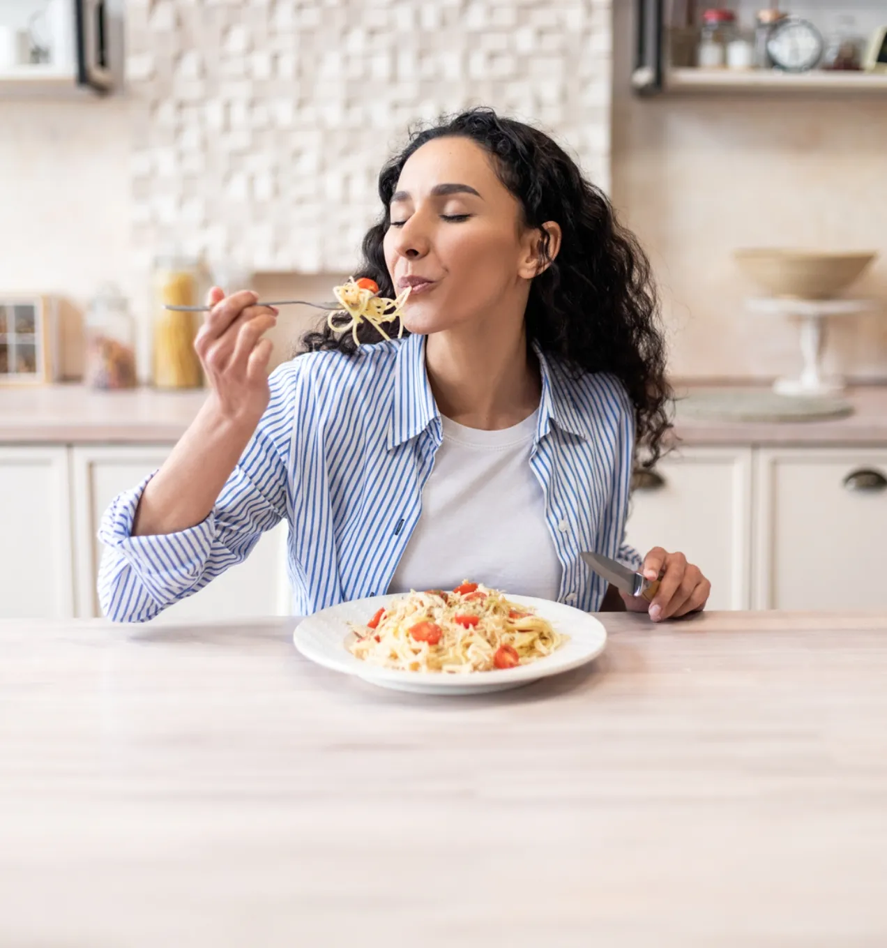 Frau in heller Küche genießt ihre. frisch zubereitete Pasta